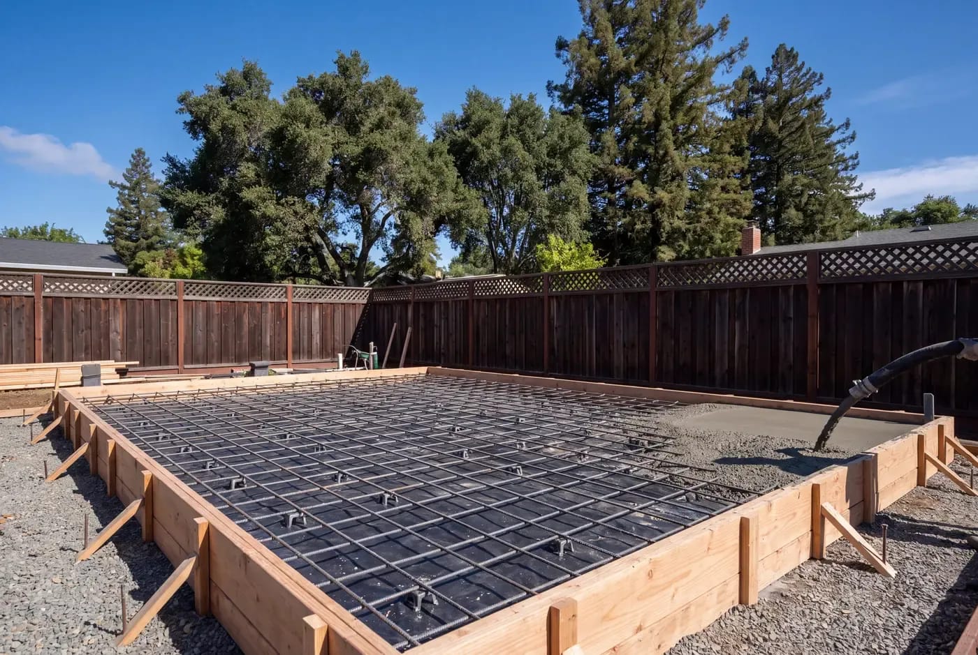 Concrete slab foundation being poured for an ADU with vapor barrier, rebar grid, and form boards visible