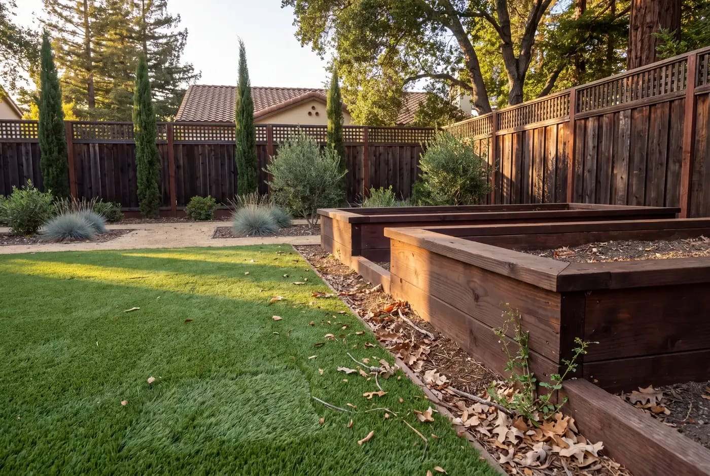 Edge detail of synthetic turf installed between two raised garden beds with decomposed granite path