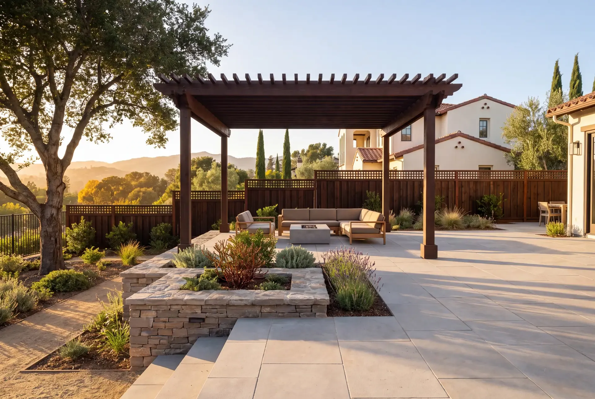A terraced hillside Los Gatos backyard with stacked-stone retaining walls, native oaks, and a pergola-shaded patio