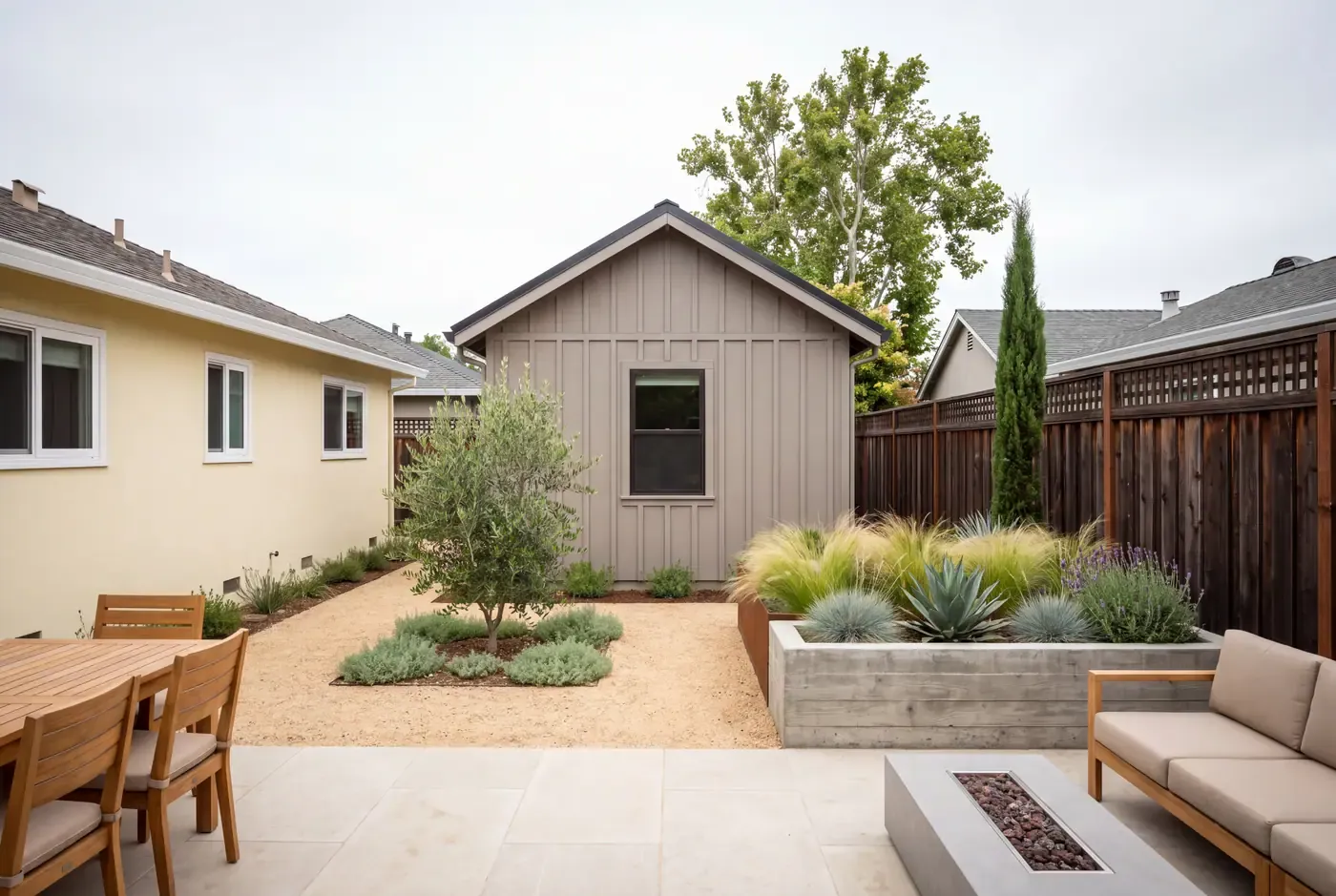 A newly completed detached ADU with a gravel courtyard in the 6-foot separation from the main house, gabled roof matching the house pitch