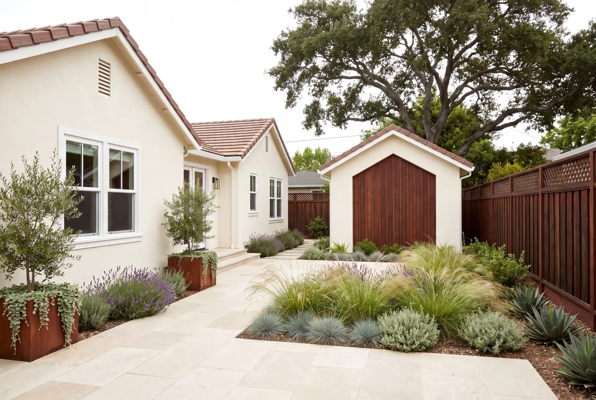 A single-family home and its matching detached ADU across a planted courtyard, sharing roof pitch and warm cream stucco