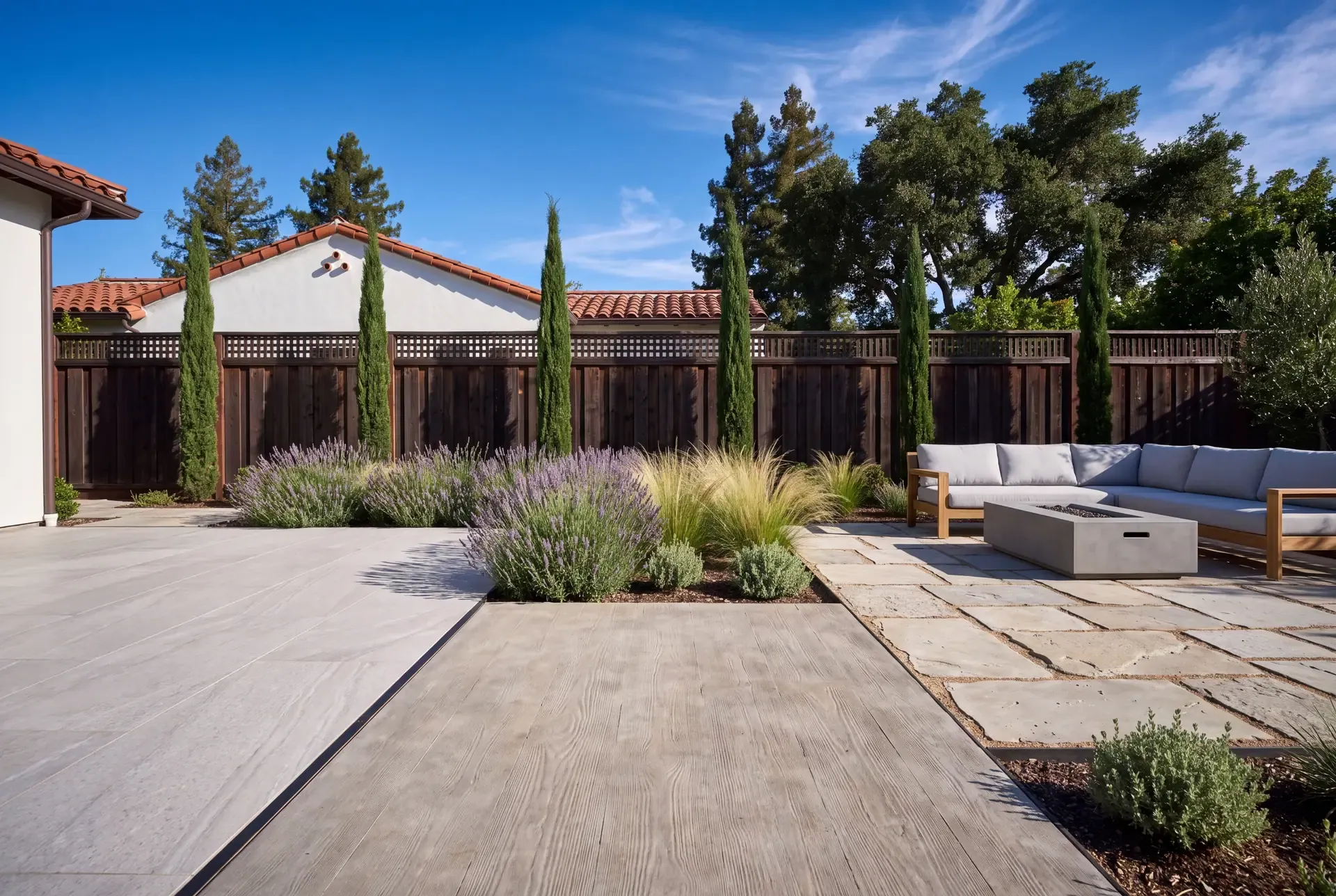 A backyard terrace with concrete pavers, natural stone, and poured concrete finishes meeting in a single patio space