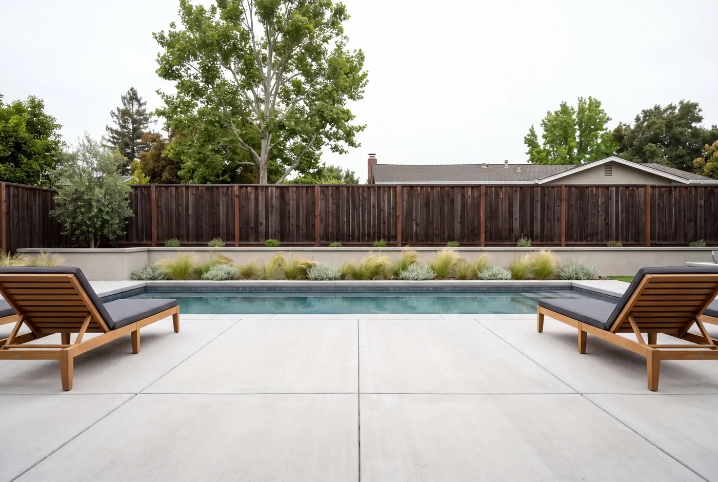 Light broom-finished concrete pool deck with control joints beside a pool