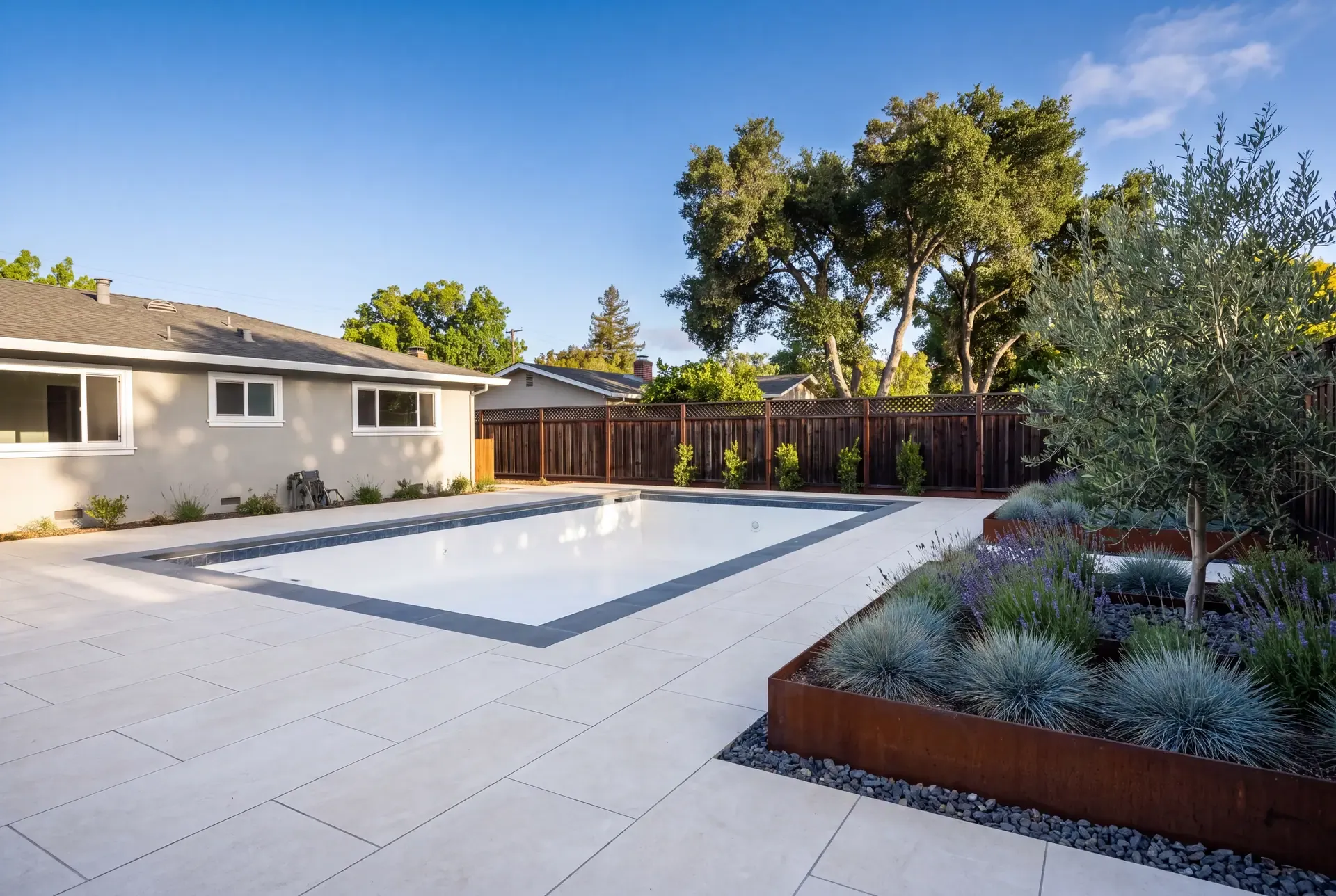 Cream porcelain paver pool deck with dark bluestone coping around a new Bay Area pool