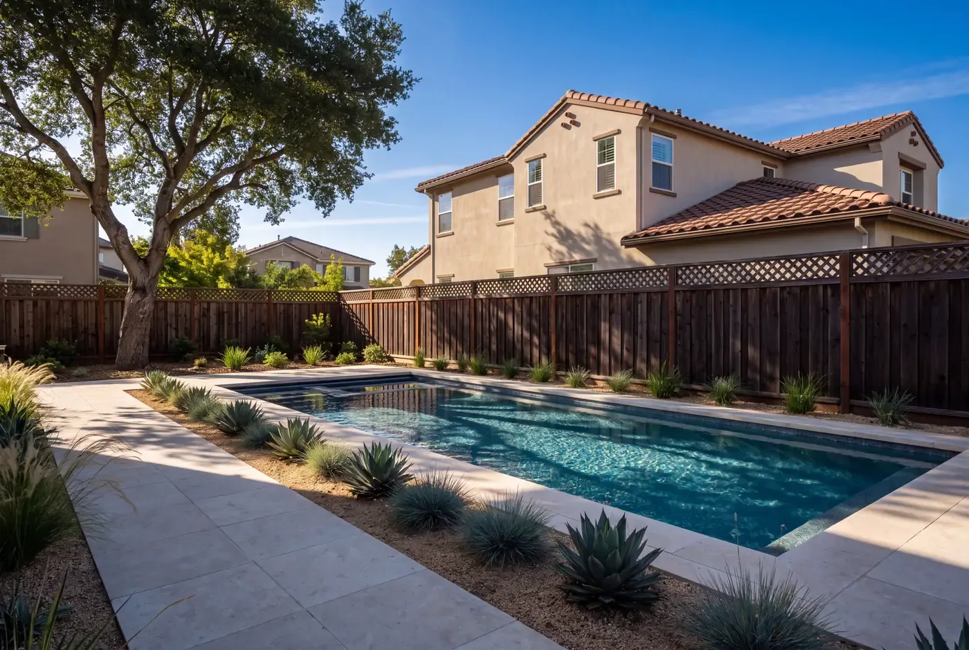 Pool deck partly shaded by a mature coast live oak in a compact backyard