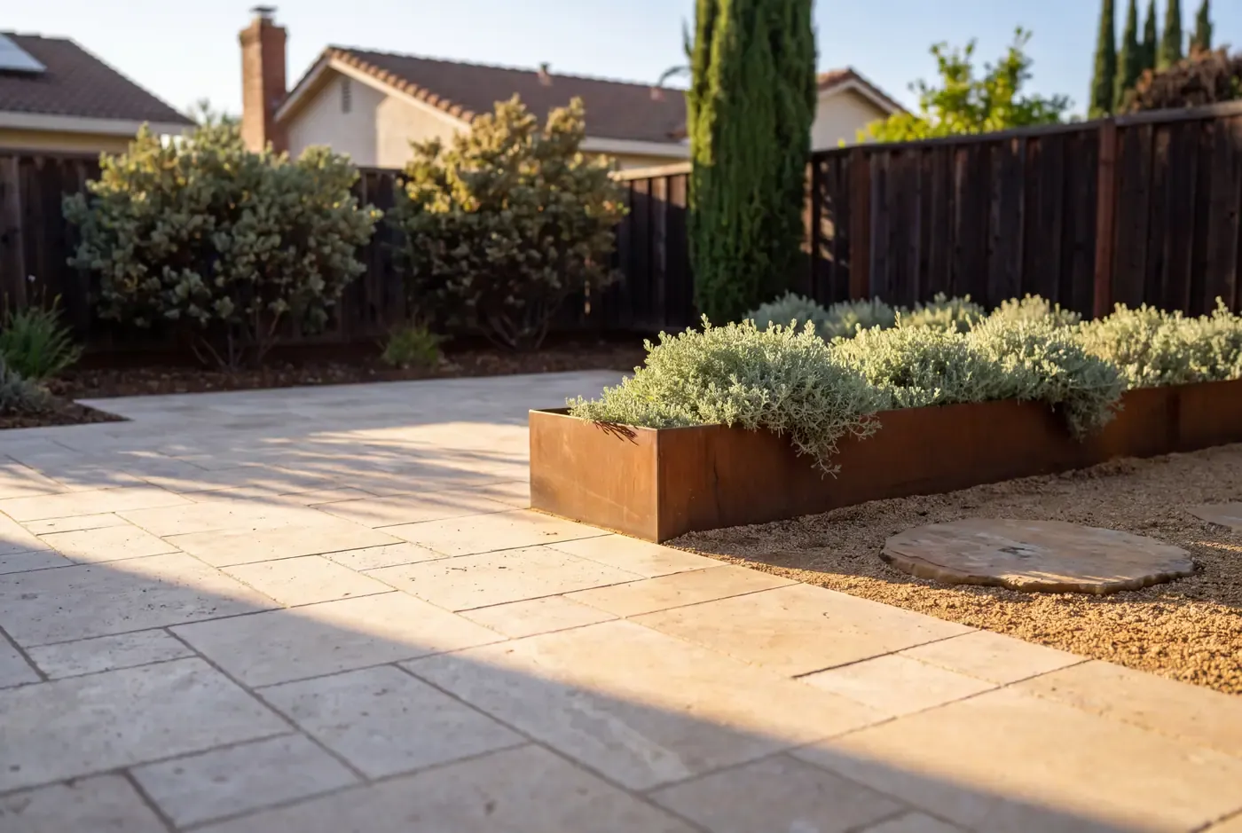 Close-up of natural-travertine paver layout showing joint pattern and stone-to-planter edge