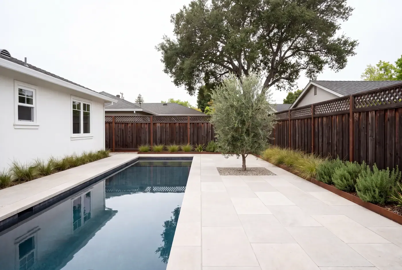 Lap pool running along one side of a narrow limestone-paved backyard